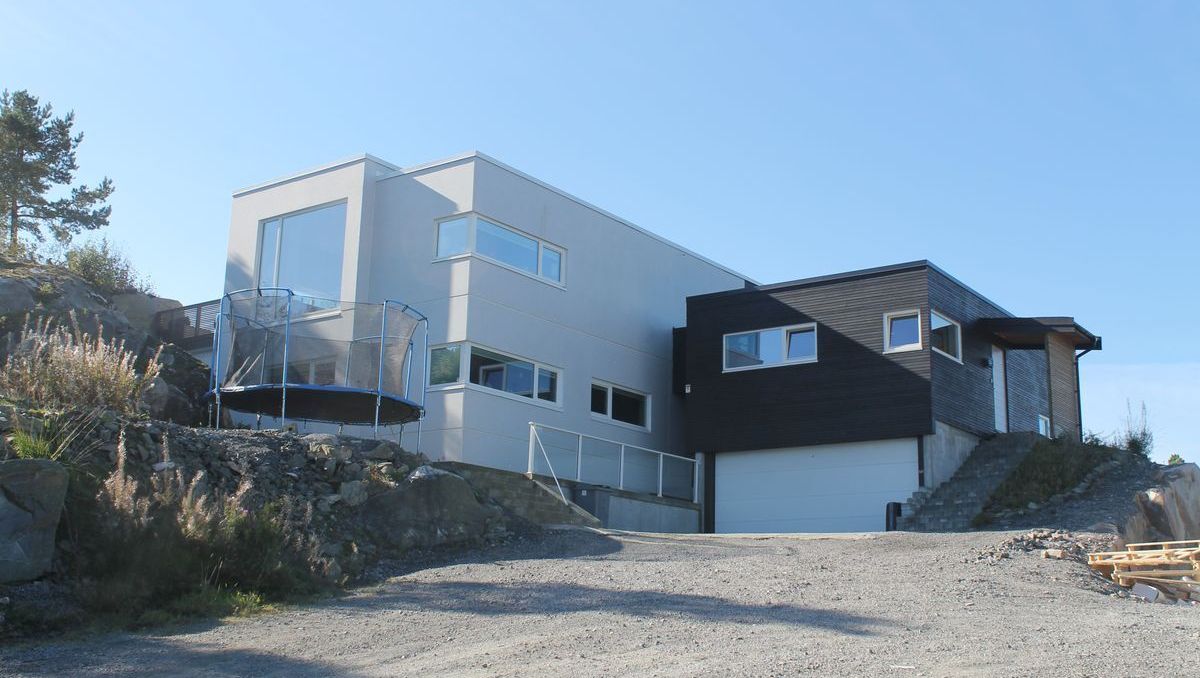 Moderne to-etasjes hus med store vinduer og balkong med glassrekkverk